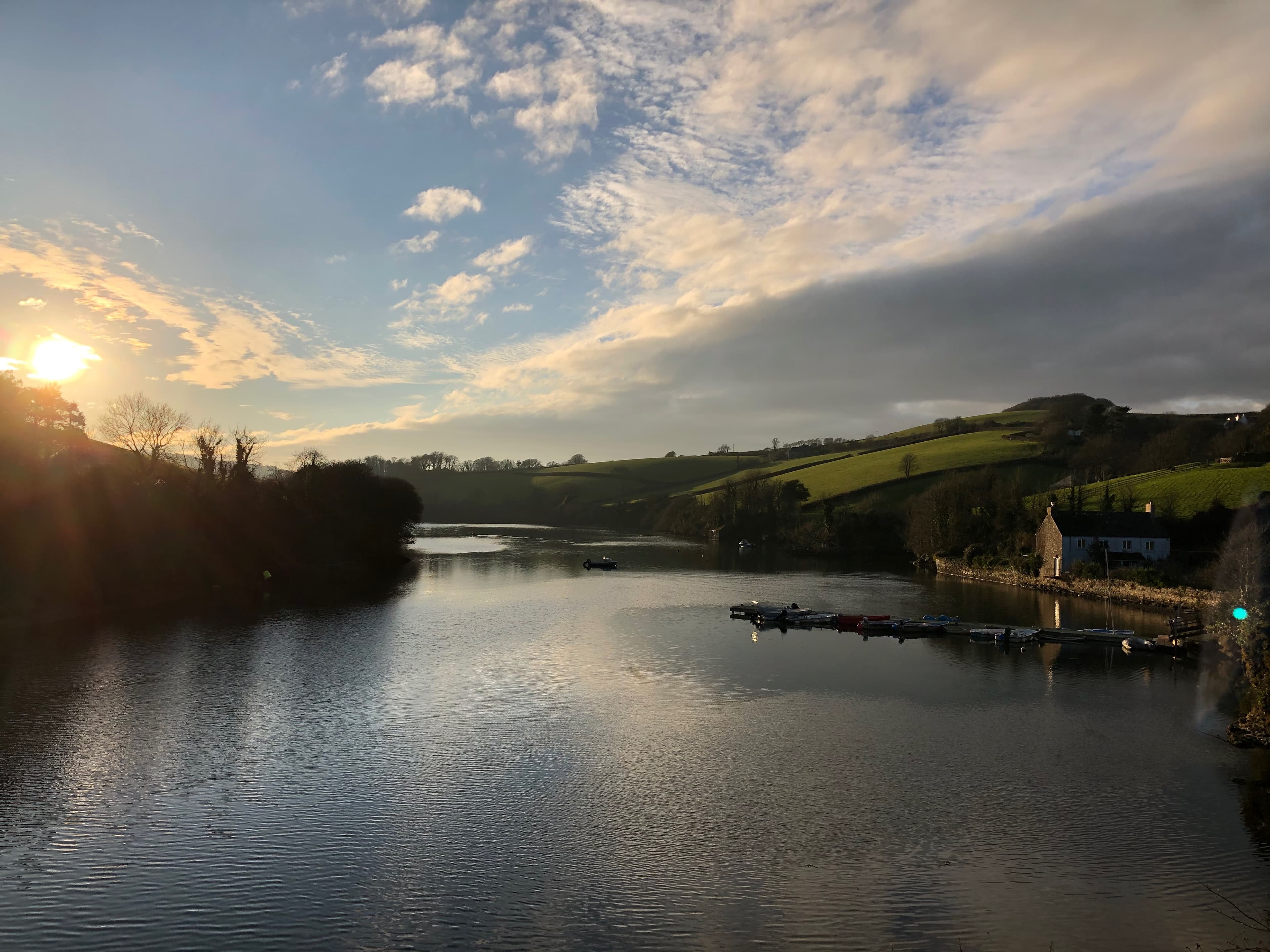South Pool creek at golden hour, with calm water, rolling hills and moored boats.